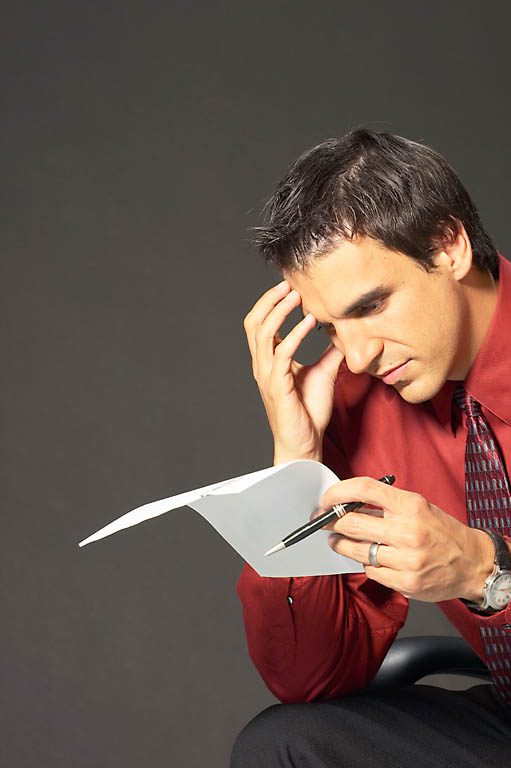 A Person is Sitting and Holding a Paper and Pen, Appearing to Be Deep in Thought