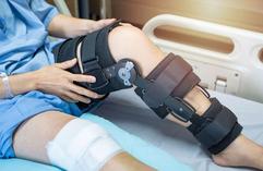 A Person’s Leg With a Knee Brace on It, Resting on a Hospital Bed